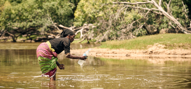 Woman collecting water in a bottle